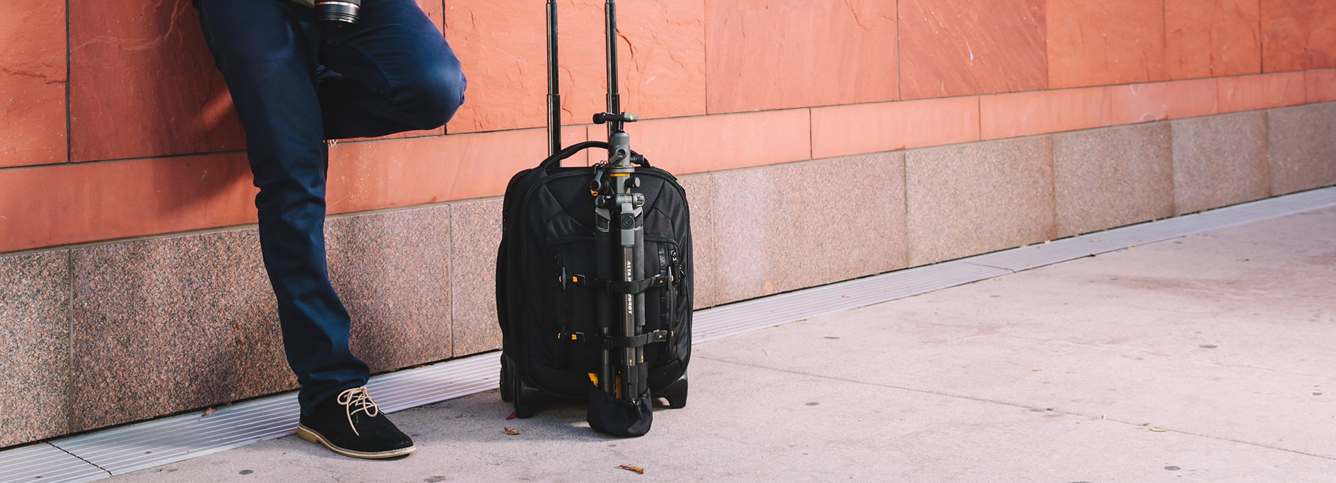 Carrello fotografico con treppiede tenuto da un utente appoggiato al muro